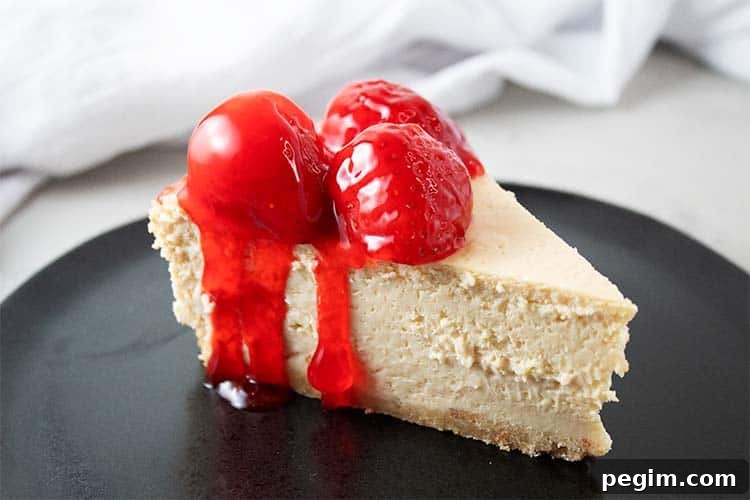 sideview of keto strawberry cheesecake on a black serving dish topped with 3 strawberries