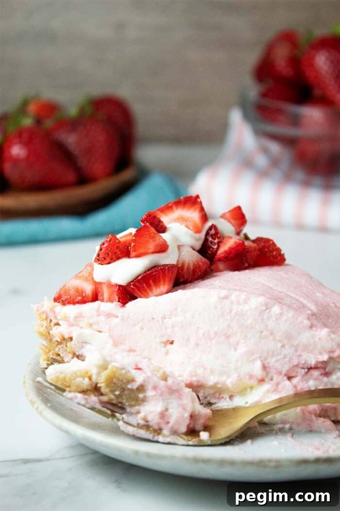 sideview of a serving of keto no-bake strawberry cheesecake on a dish topped with sliced strawberries and whipped cream