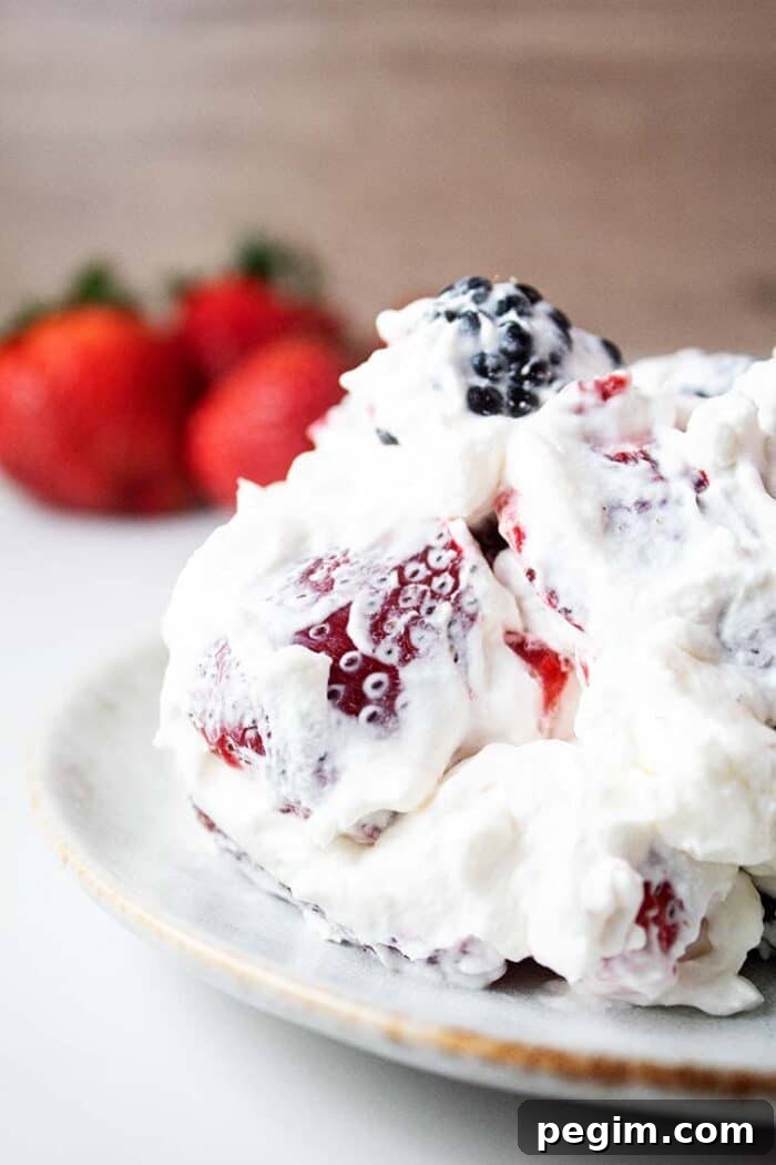 sideview of healthy keto cheesecake fluff on a white serving dish with strawberries in the background