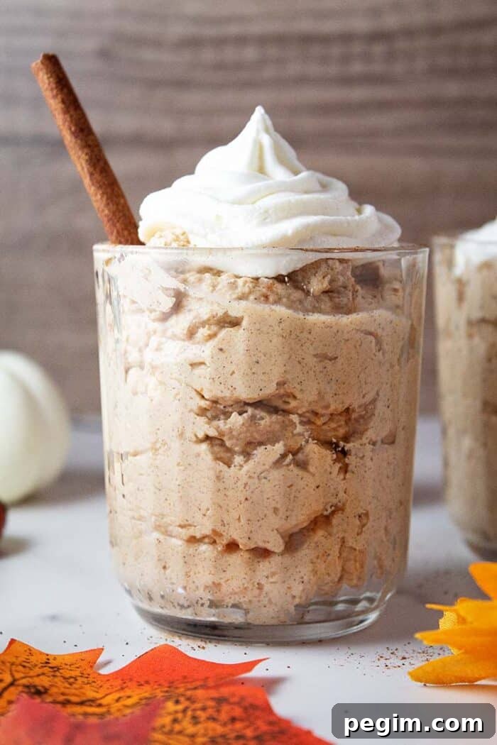 sideview of keto pumpkin fluff in serving glass topped with whipped cream and cinnamon stick straw