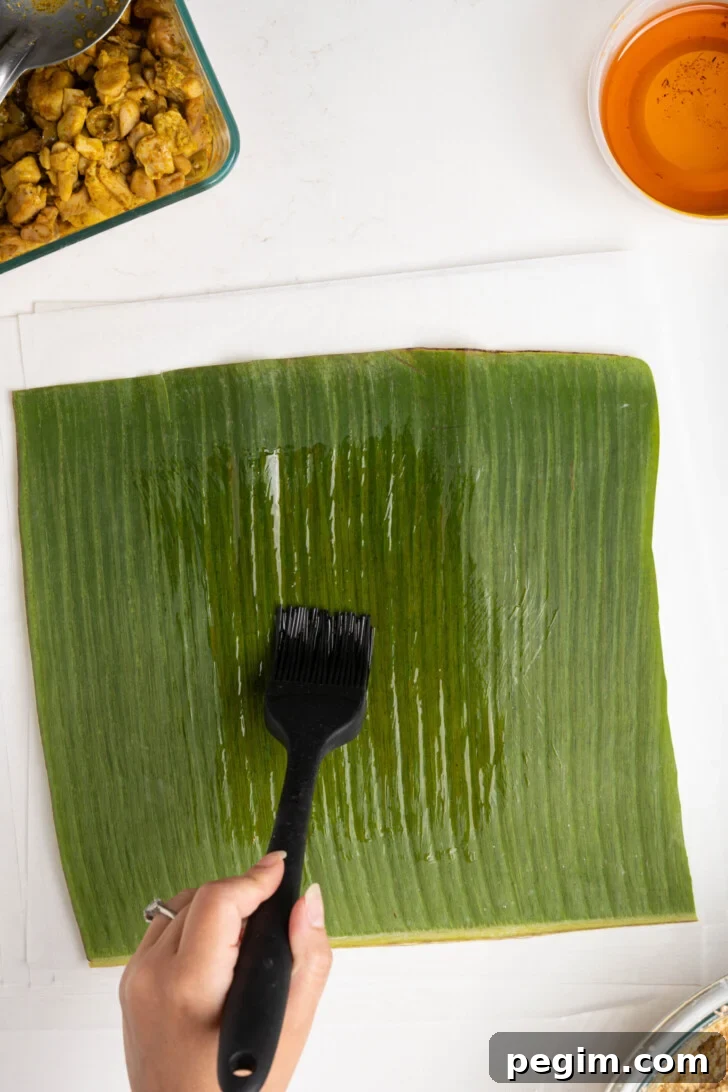 A banana leaf being brushed with oil.