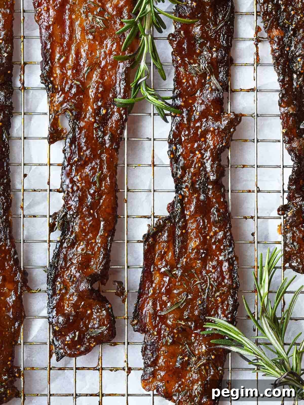 Oven-baked fig jam candied bacon with fresh rosemary.