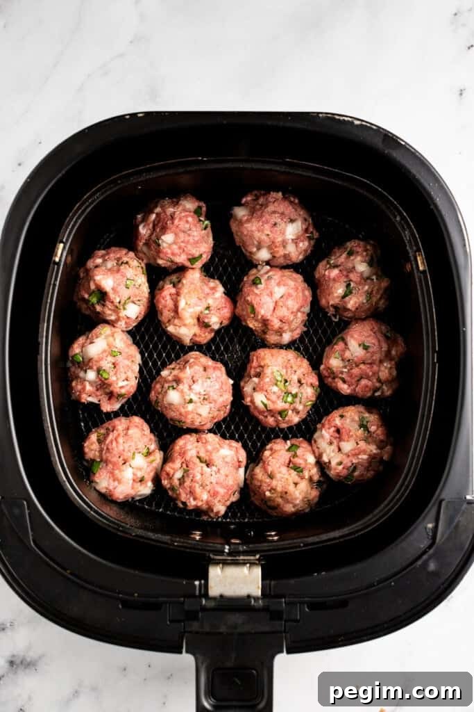 Uncooked meatballs in an air fryer.