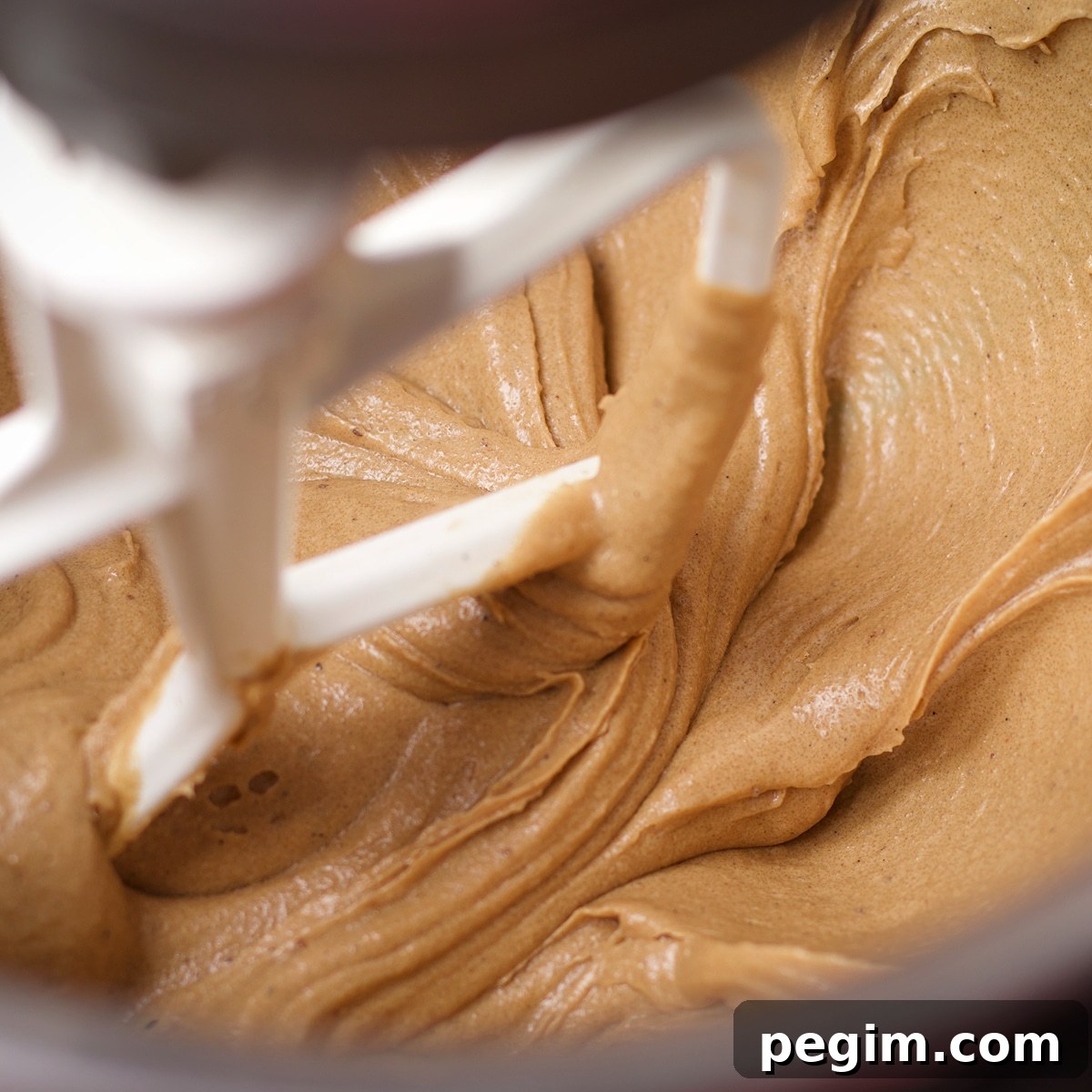 Beating egg whites into brown sugar and brown butter with an electric mixer.