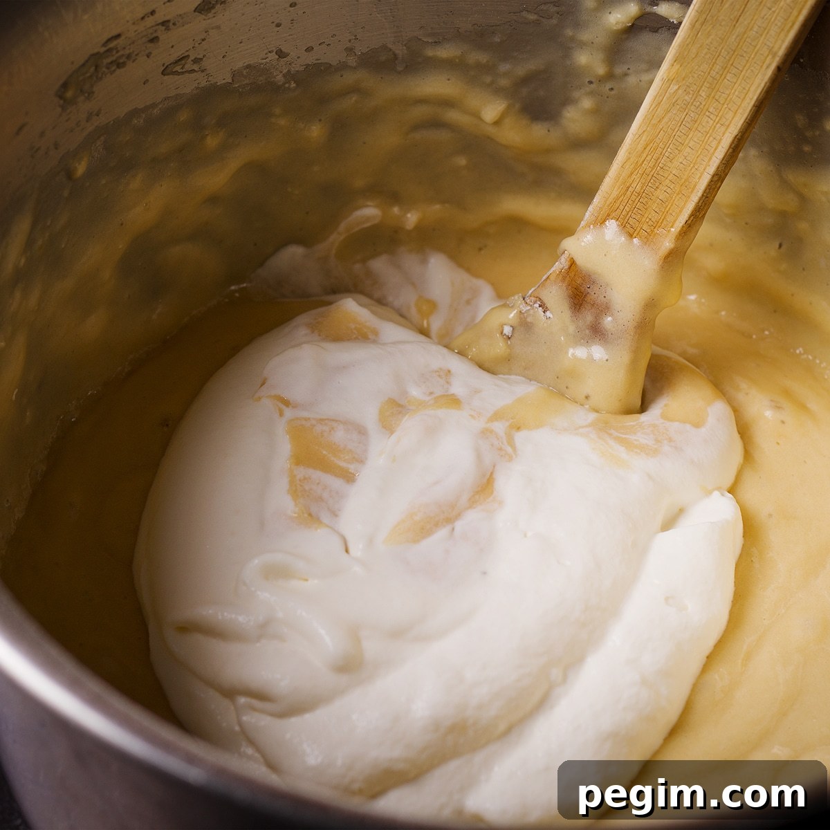 Using a wooden spoon to fold whipped cream into cake batter.