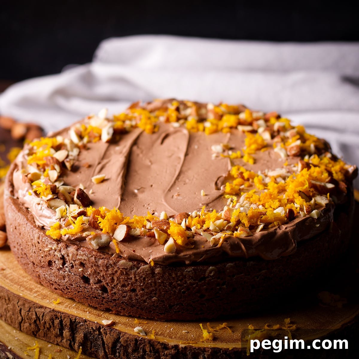 A one layer chocolate almond cake that's been frosted with chocolate orange buttercream and decorated with chopped almonds and orange zest.