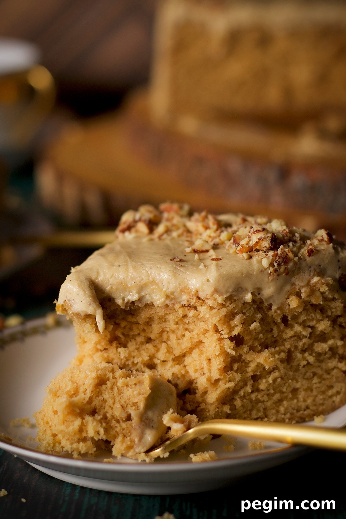 Someone using a fork to cut a bite from a slice of brown butter cake frosted with maple miso brown butter frosting.