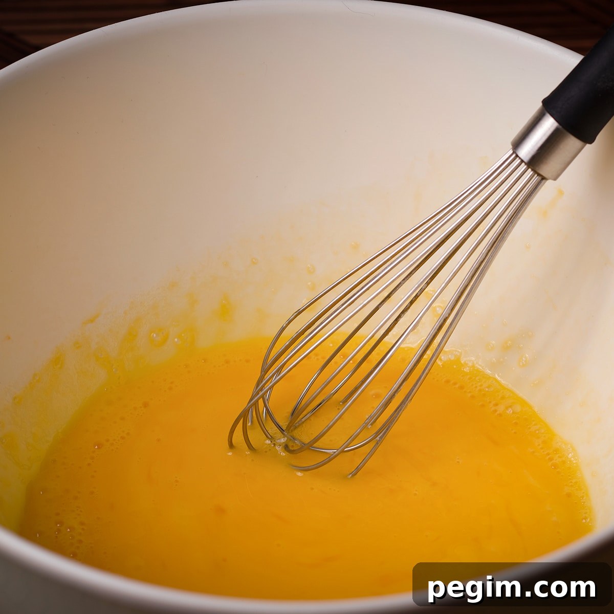 A bowl filled with eggs that have been whisked together.