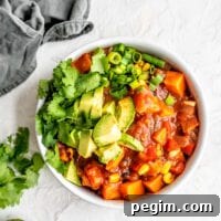 A bowl of sweet potato chili topped with avocado, cilantro and green onion.