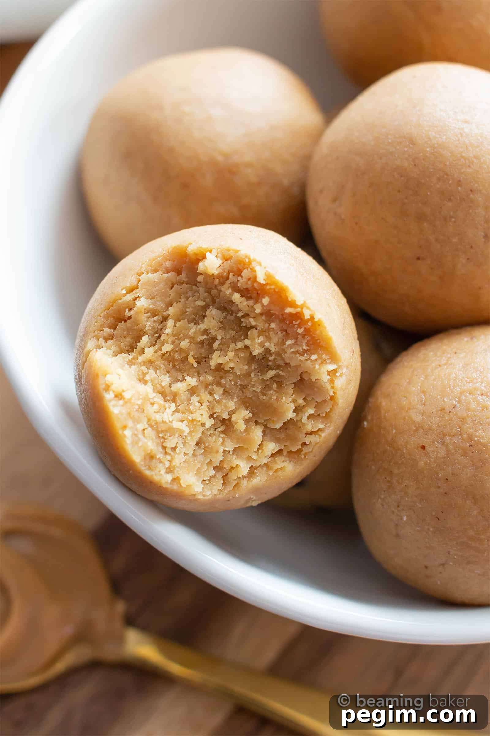 3-Ingredient Keto Peanut Butter Bites — Low-Carb Snack 2 Plate of keto energy balls with a bite taken out of one of them.