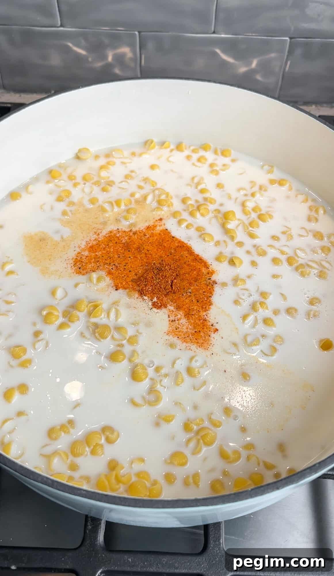 adding pasta, broth, cream, and seasonings into a pot