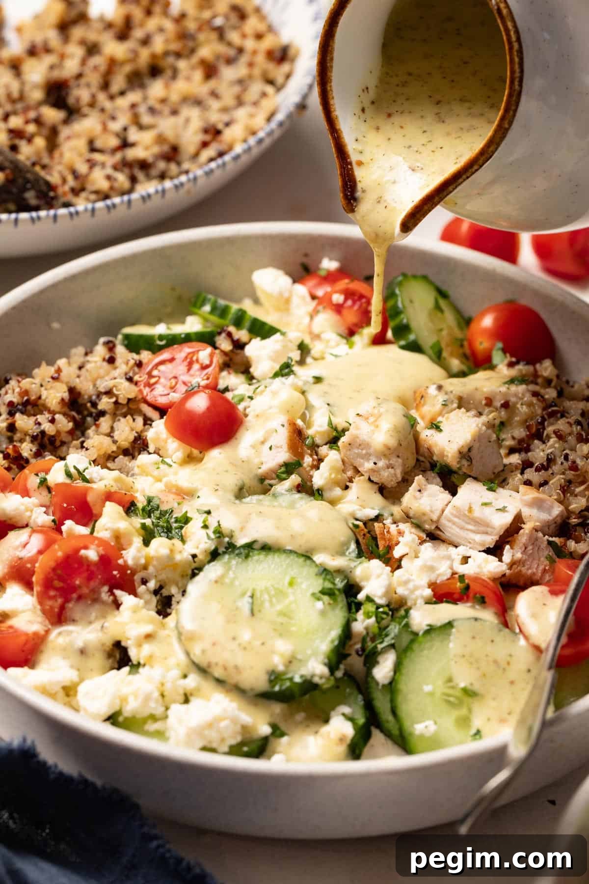 Pouring the Mediterranean vinaigrette on top of the chicken and quinoa.