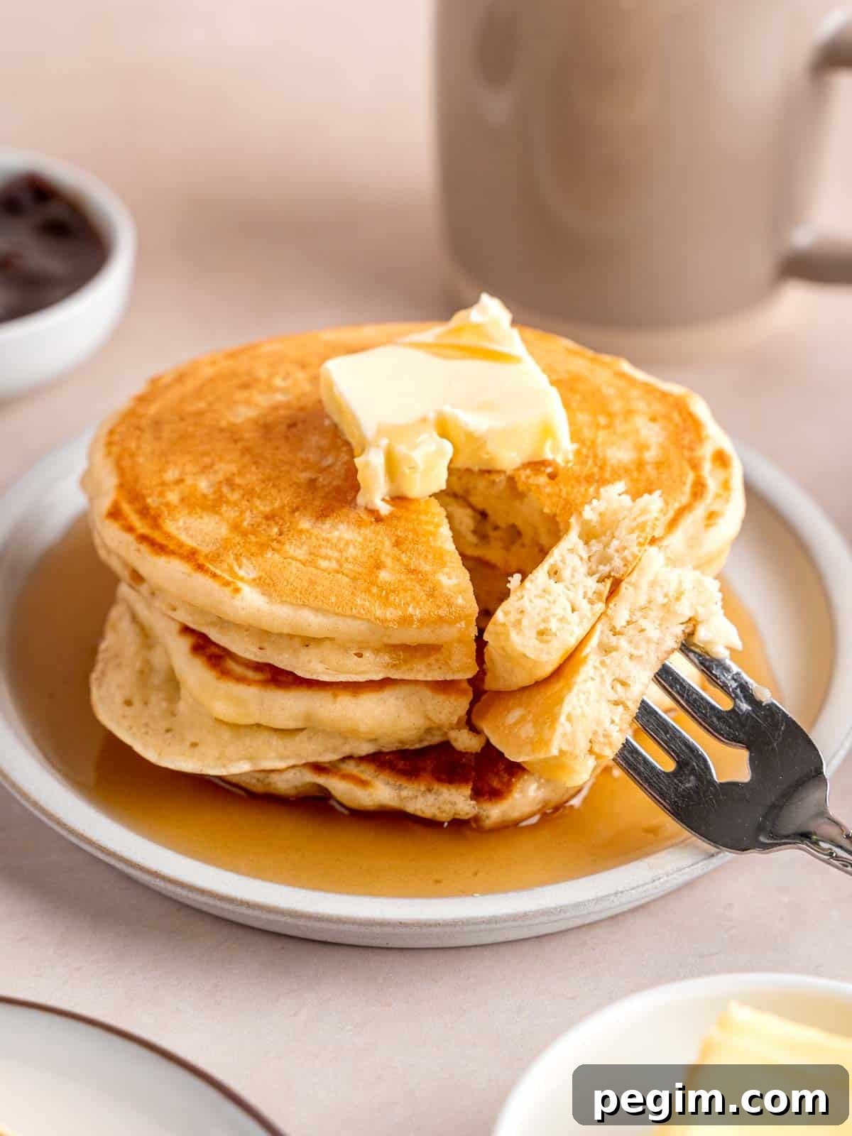A stack of fluffy kefir pancakes topped with butter and maple syrup.