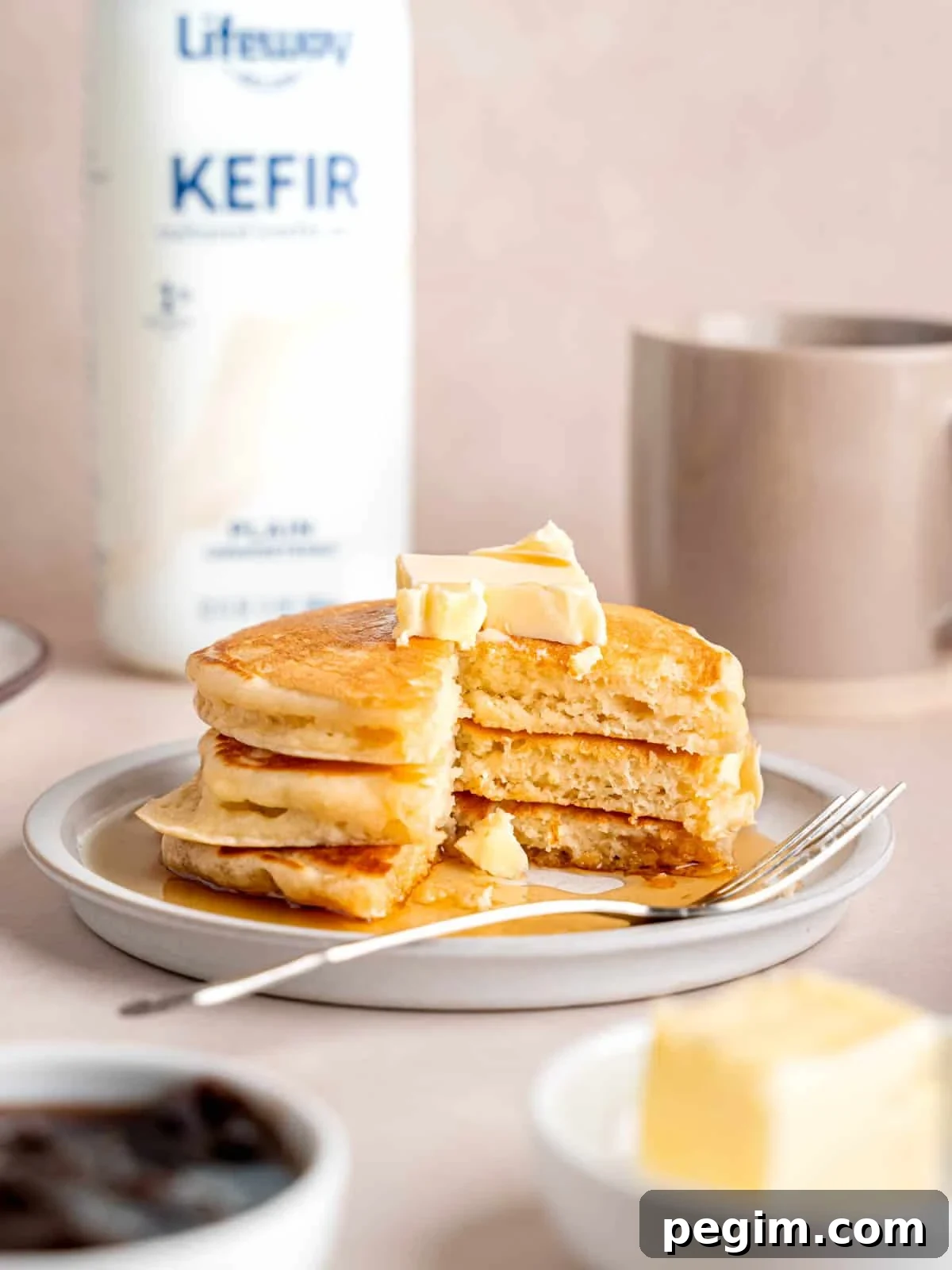 A stack of fluffy pancakes on a plate next to a bottle of Lifeway lowfat kefir.
