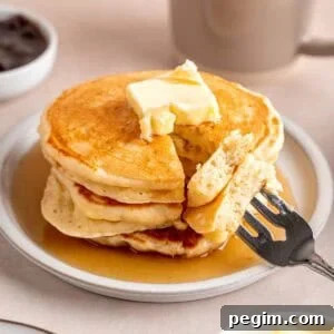 A stack of fluffy kefir pancakes topped with butter and maple syrup.