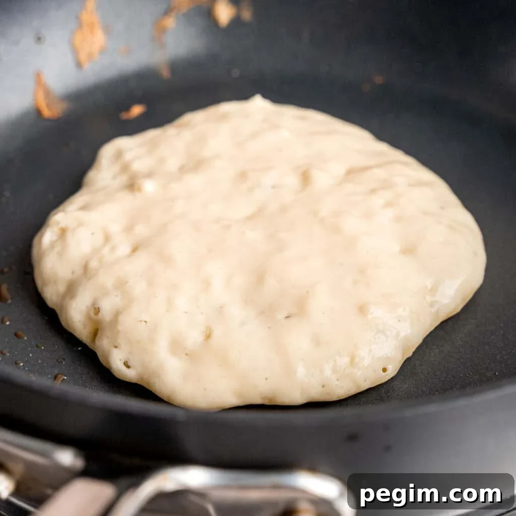 Pancake batter cooking on a hot skillet.
