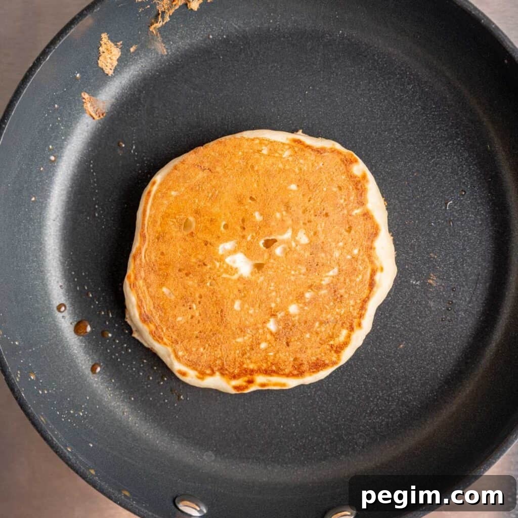 A kefir pancake on a skillet cooked to golden brown.