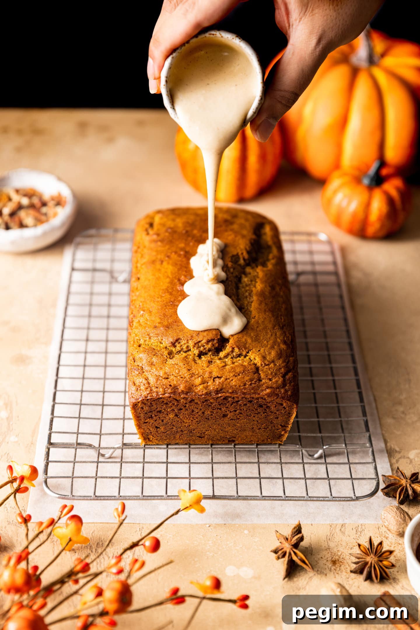 Maple glaze being poured on top of pumpkin bread loaf