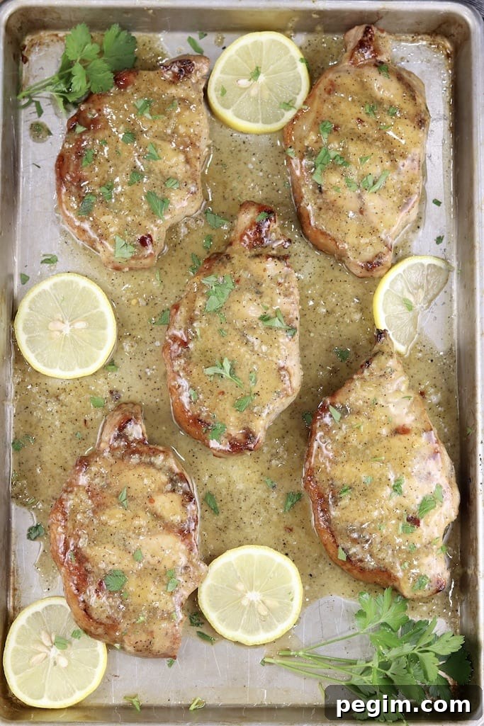 Sheet pan of 5 grilled pork chops with lemon garlic sauce, fresh lemon slices and fresh parsley
