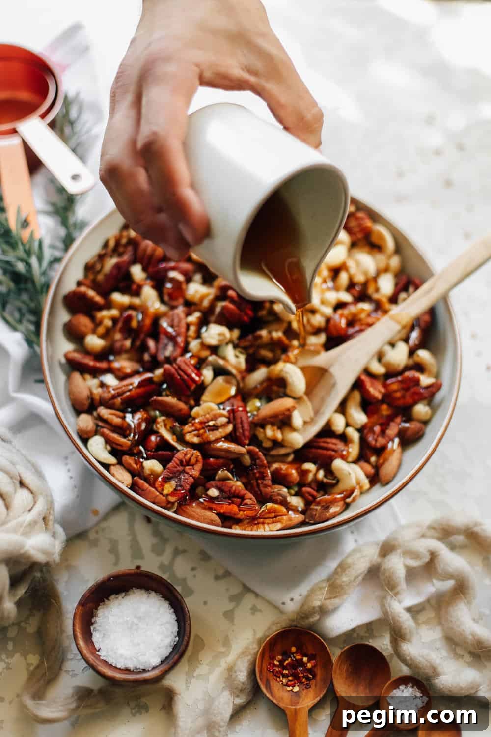 A large bowl of mixed nuts with syrup being poured. 