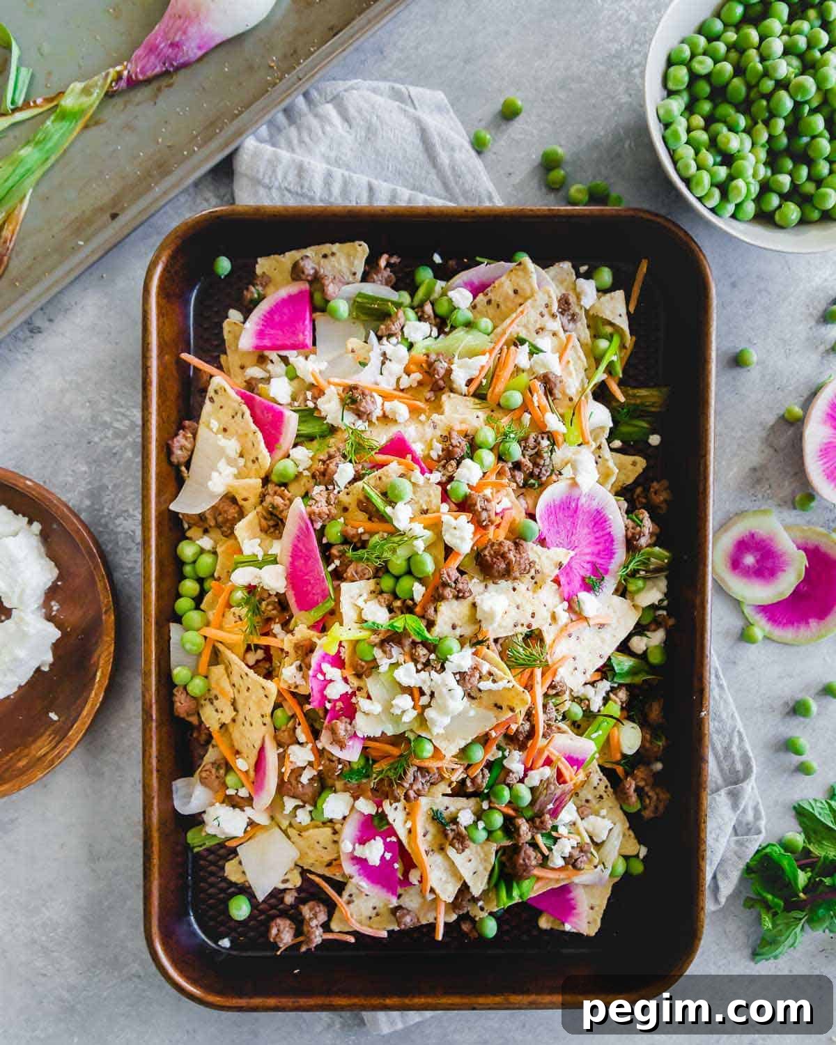 These ground American lamb nachos with carrots, onions, peas and radishes are topped with crumbled feta cheese for a bright and fresh spring take on nachos. Enjoy them straight off the baking sheet for an easy seasonal dinner or appetizer.