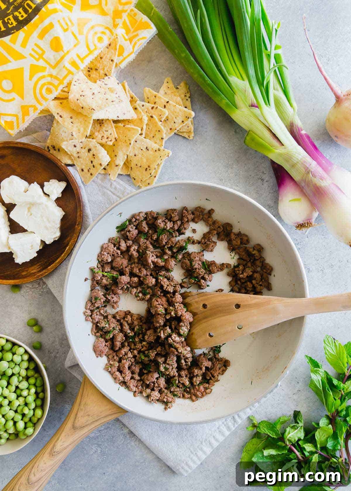 lamb nachos use ground American lamb with a bunch of early spring vegetables and lots of crumbled feta cheese for a fun seasonal twist to traditional nachos.