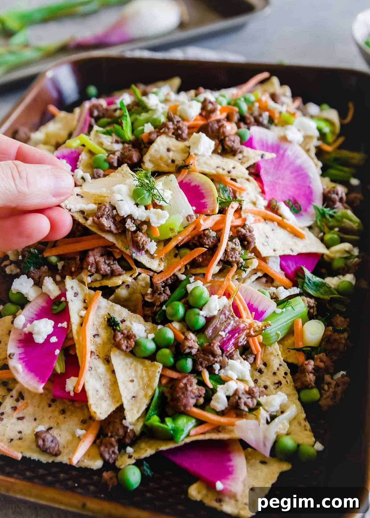 A fun spring spin on traditional nachos, these nachos use ground lamb seasoned with dill and oregano and lots of fresh spring vegetables.
