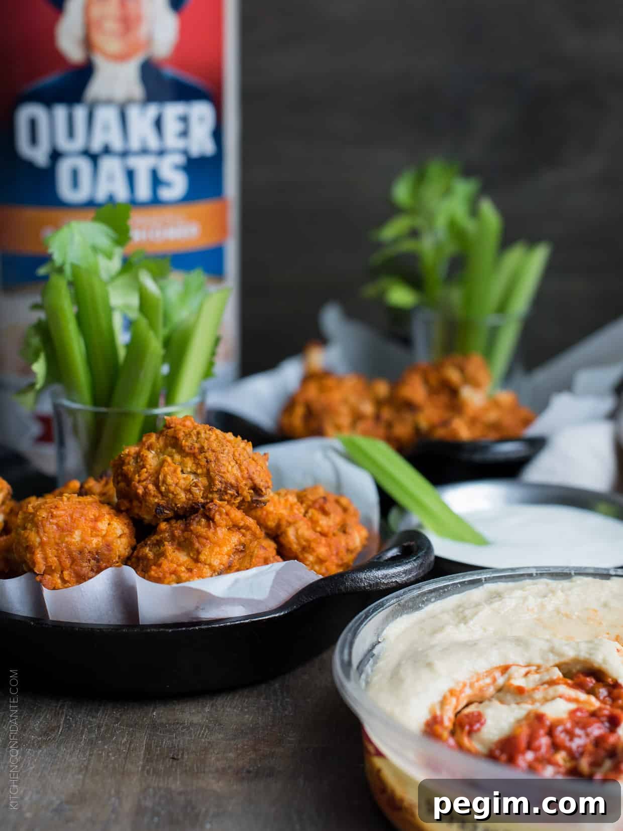 Hummus Battered Buffalo Cauliflower "Wings" served in small cast iron skillets alongside stalks of celery.