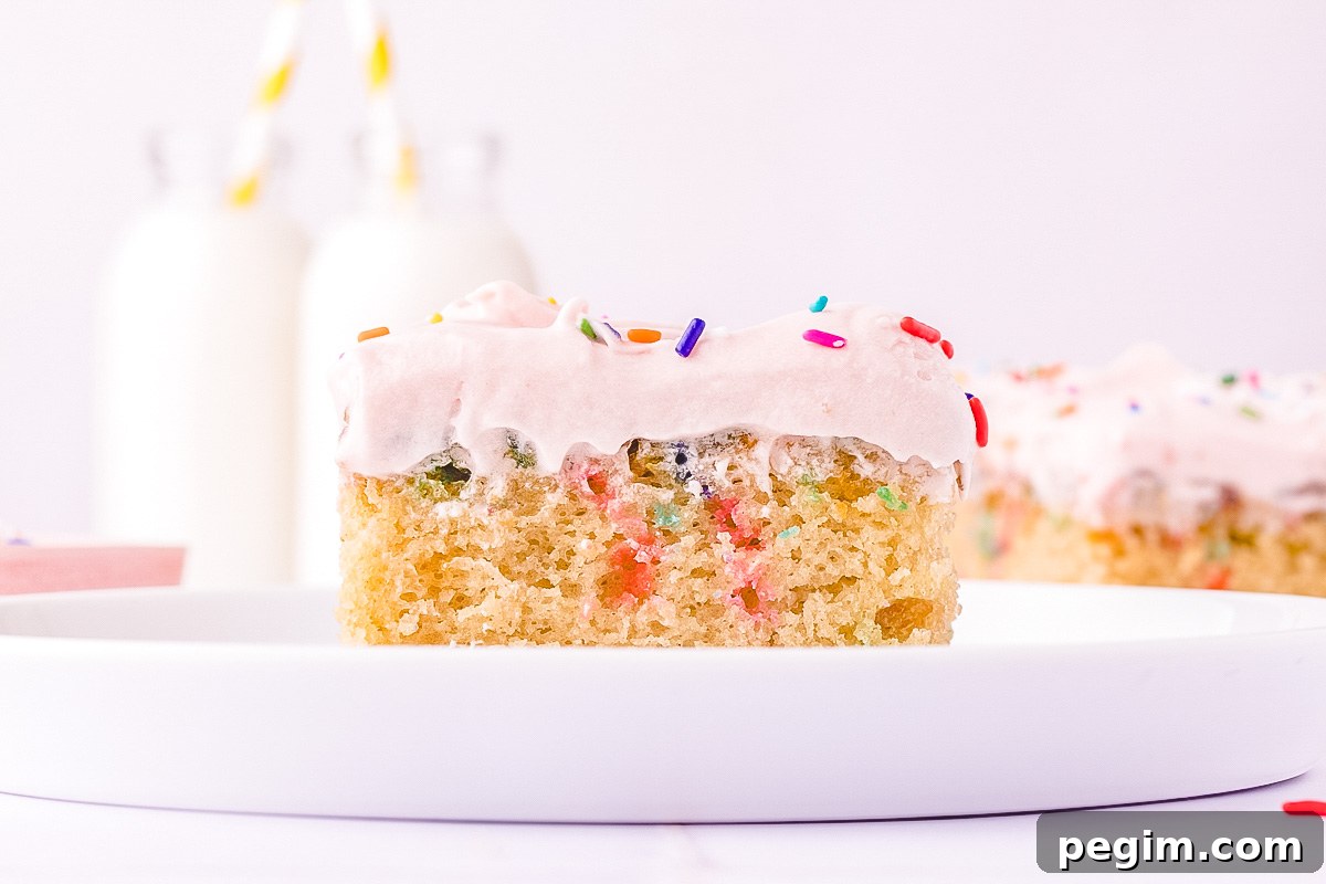 A piece of funfetti shet cake on a white plate with a glass of milk in the background.