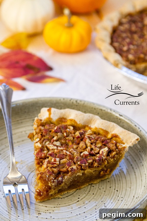 A piece of Bourbon Pecan Pie on a plate with a fork and some pumpkins in the background