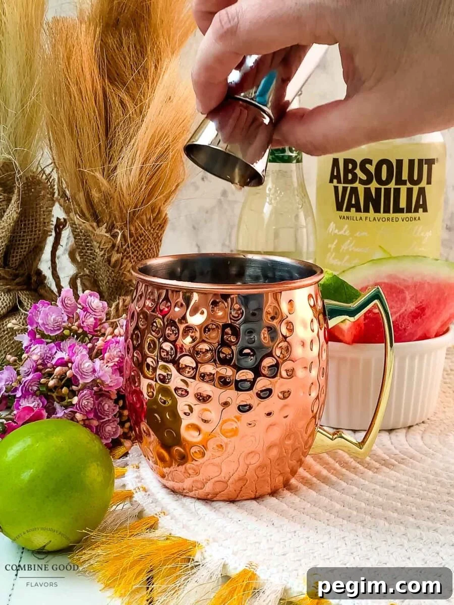 Adding watermelon syrup to the copper mug.