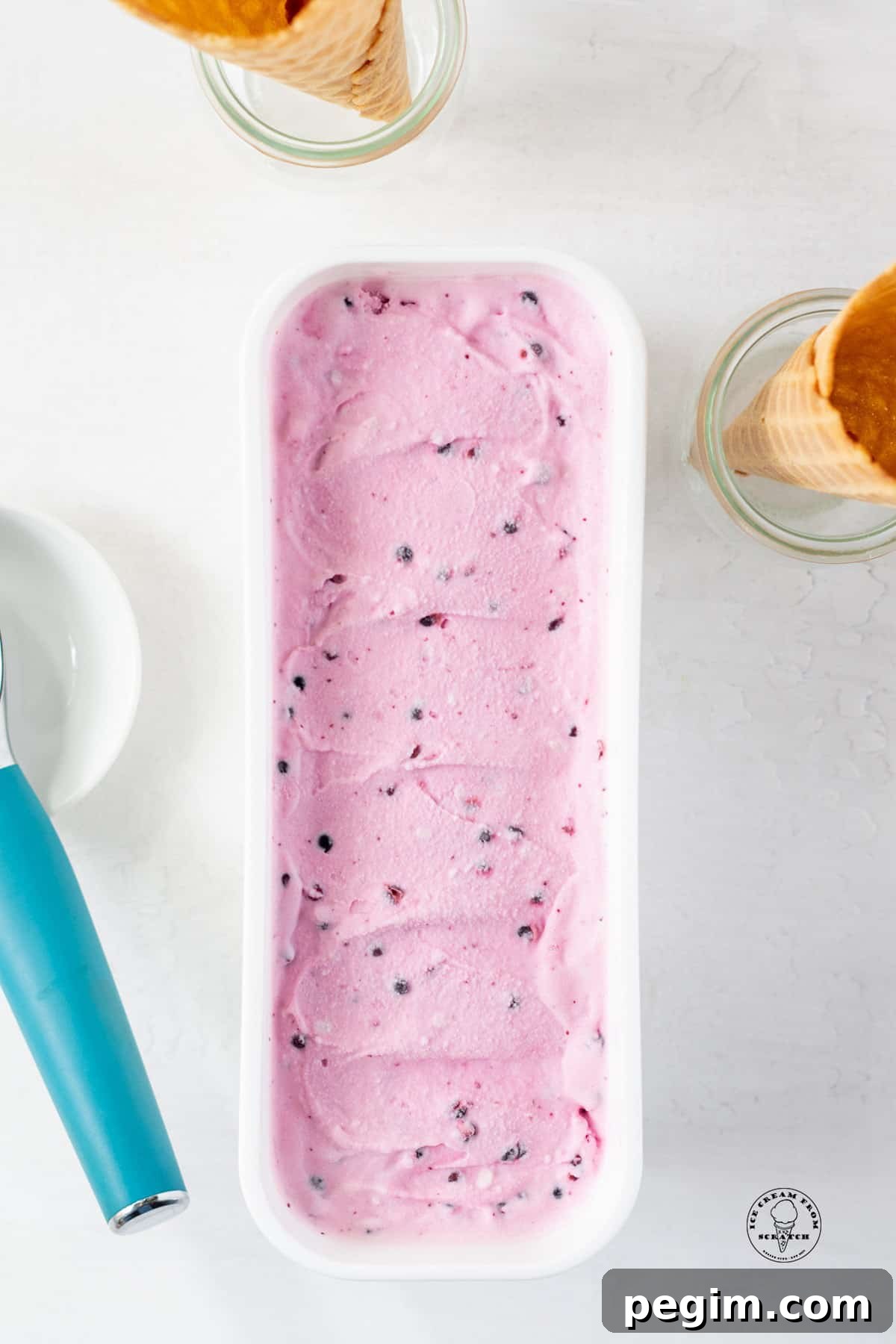 a long white ice cream container filled with light purple huckleberry ice cream.