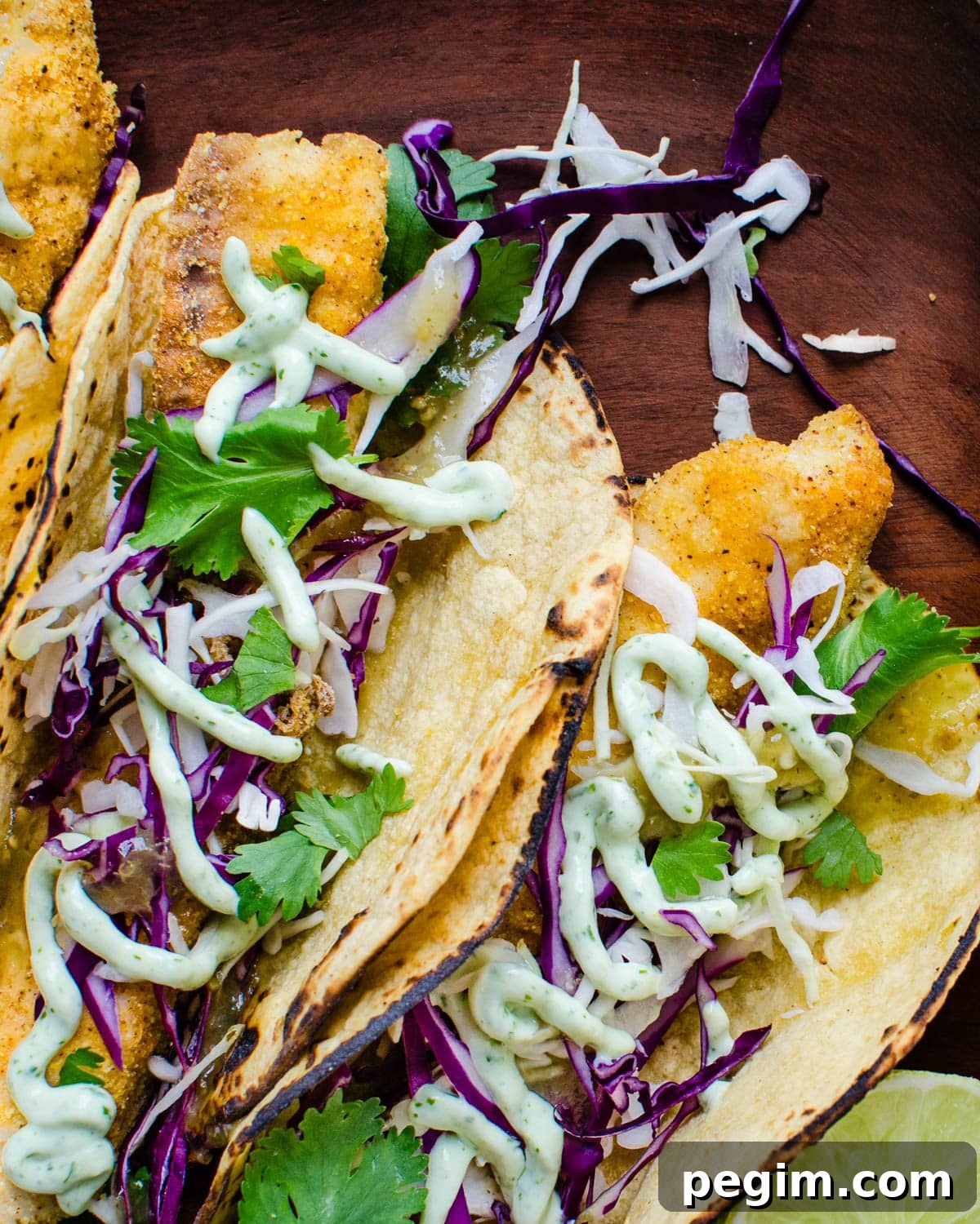 Serving three dressed fish tacos with crema and cilantro. 