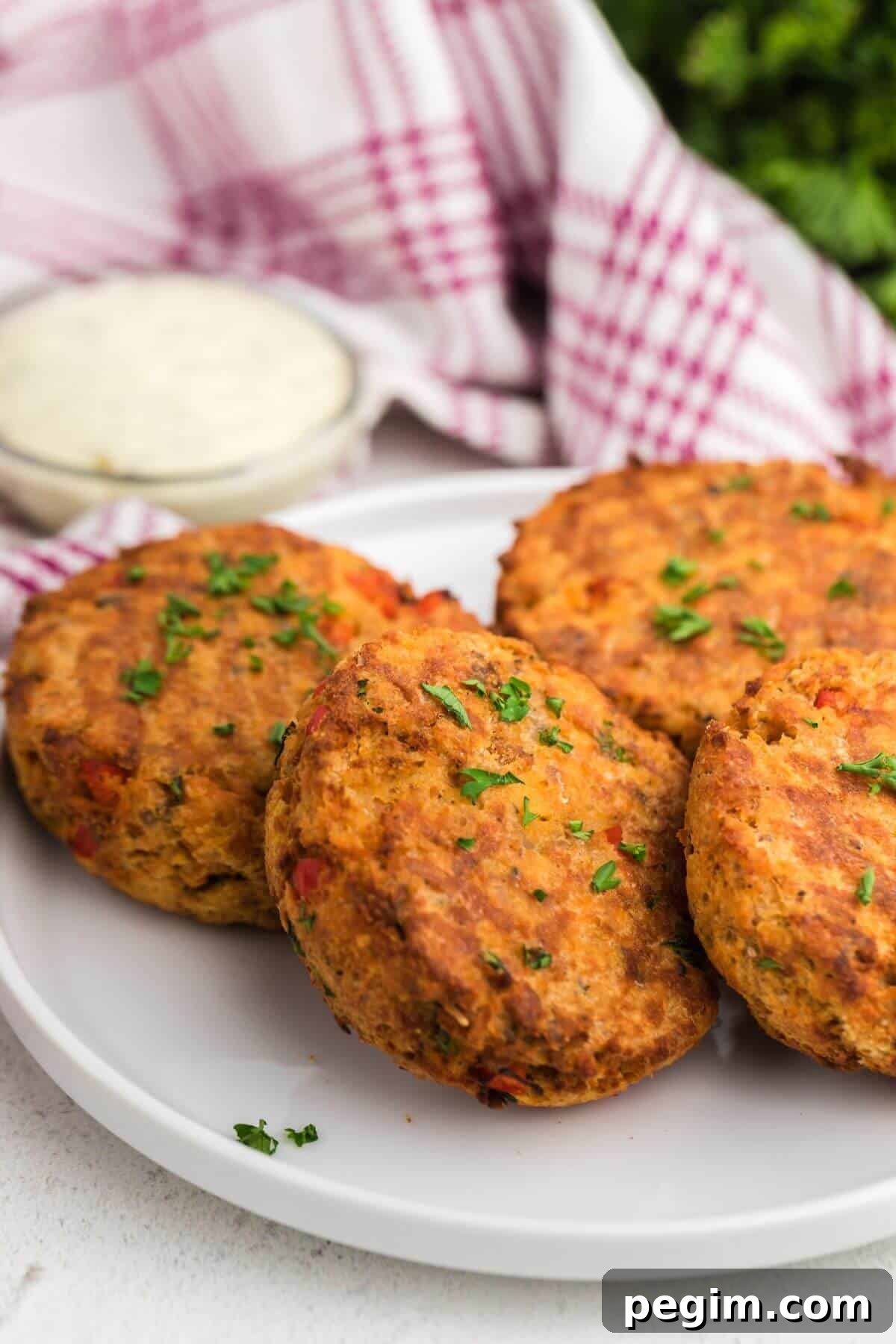 Golden patties on a white plate with a small bowl of tartar sauce.