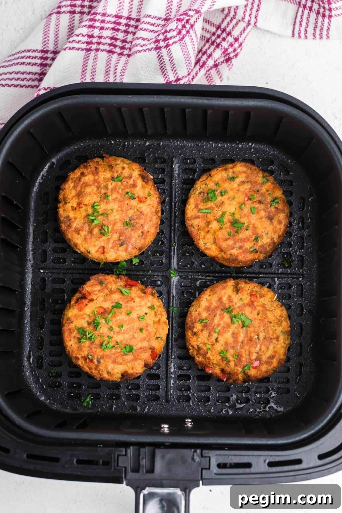 Golden brown salmon patties in the air fryer basket after being cooked.