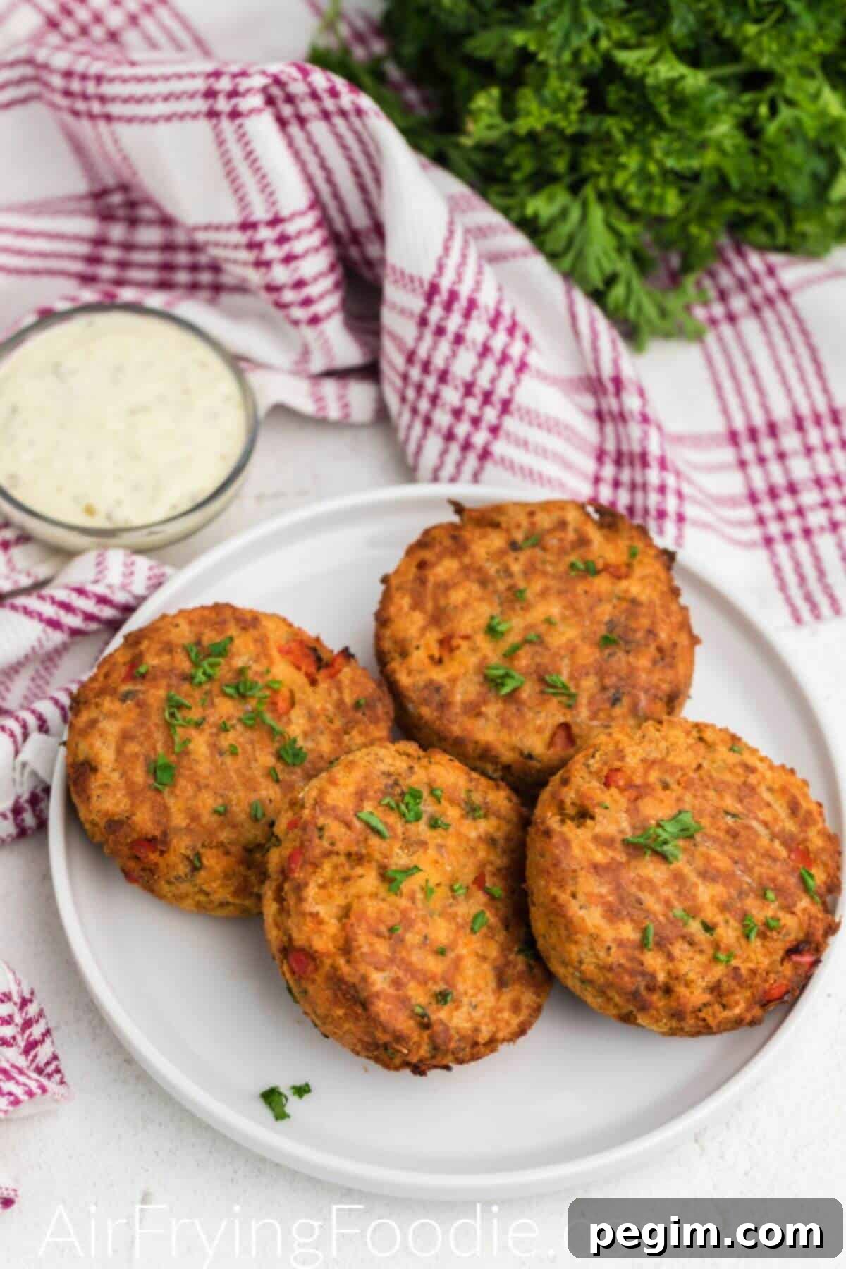Golden crispy salmon cakes stacked on a white plate.