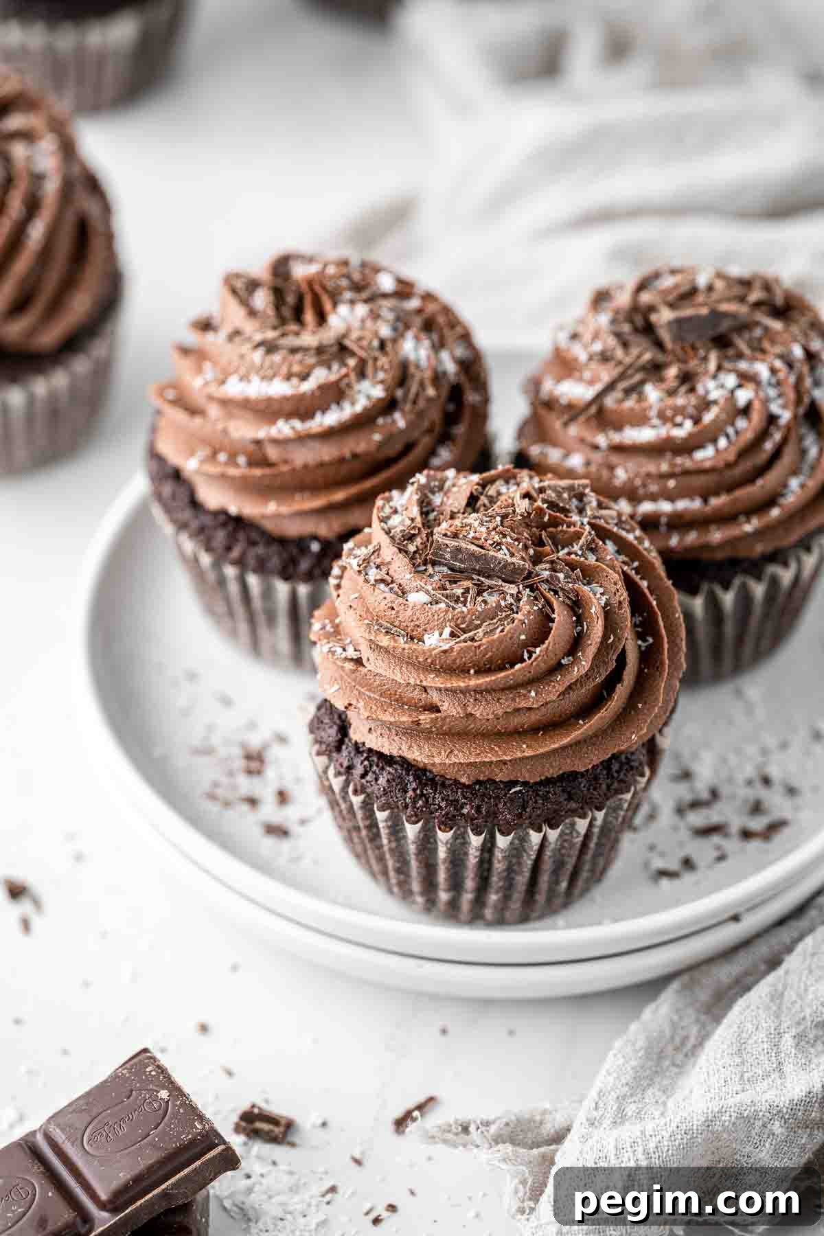 Three chocolate and coconut cupcakes on a white plate.