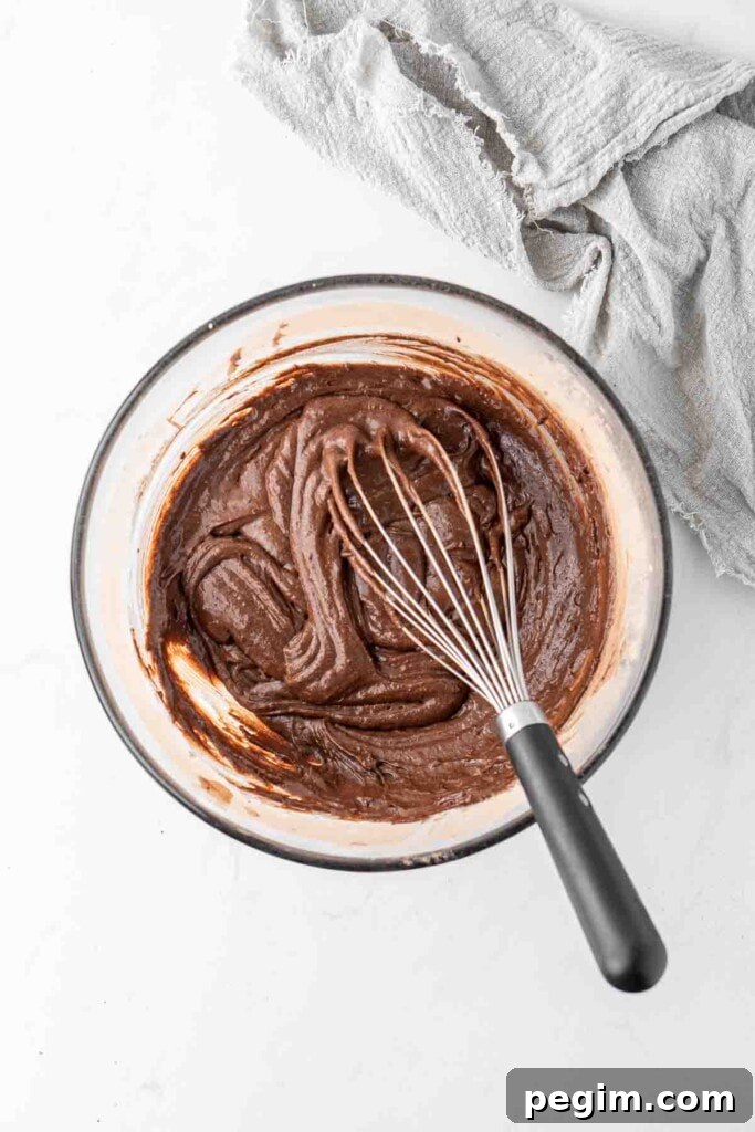 Cupcake batter in a bowl with a whisk.