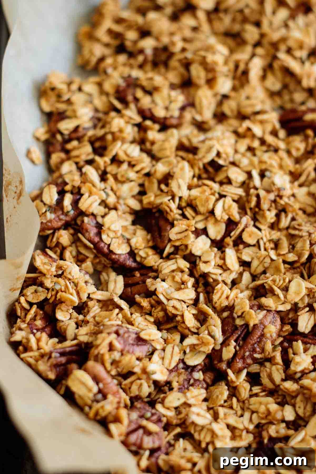 Granola spread on a lined baking sheet.