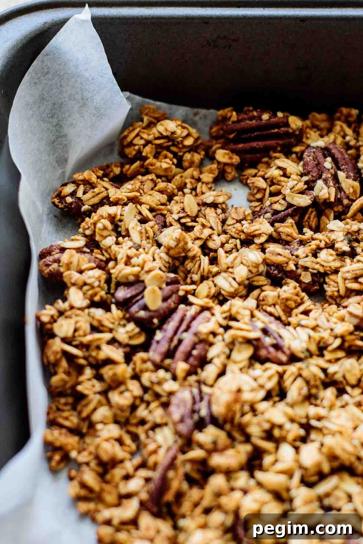 Pumpkin granola after baked in a lined baking sheet.