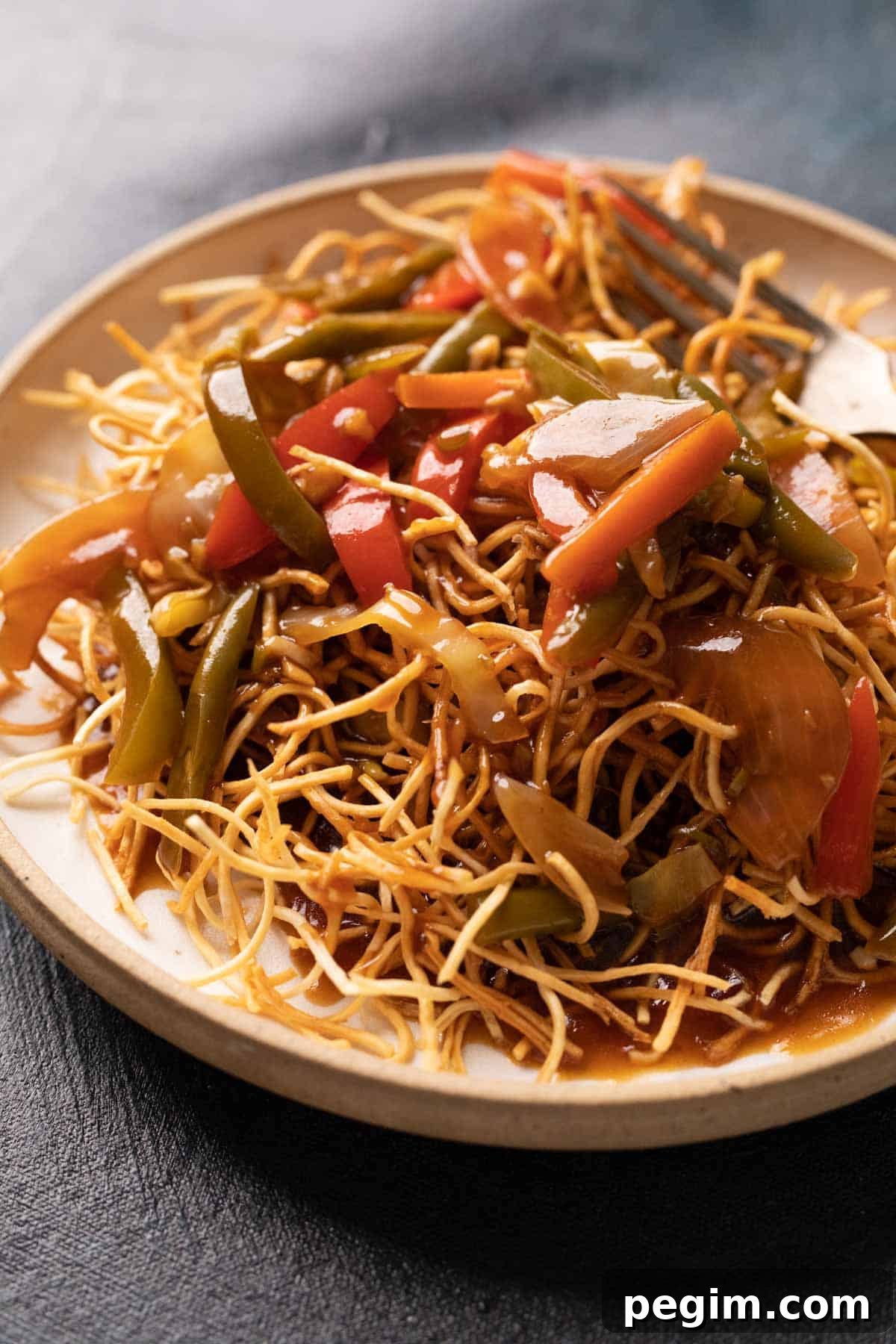 American Chopsuey served on crispy fried noodles in a white plate with a fork
