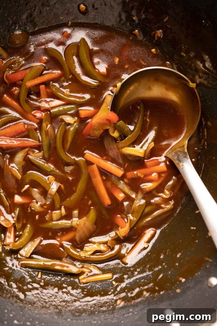 Sweet, sour tangy american chopsuey pictured in a wok with a ladle