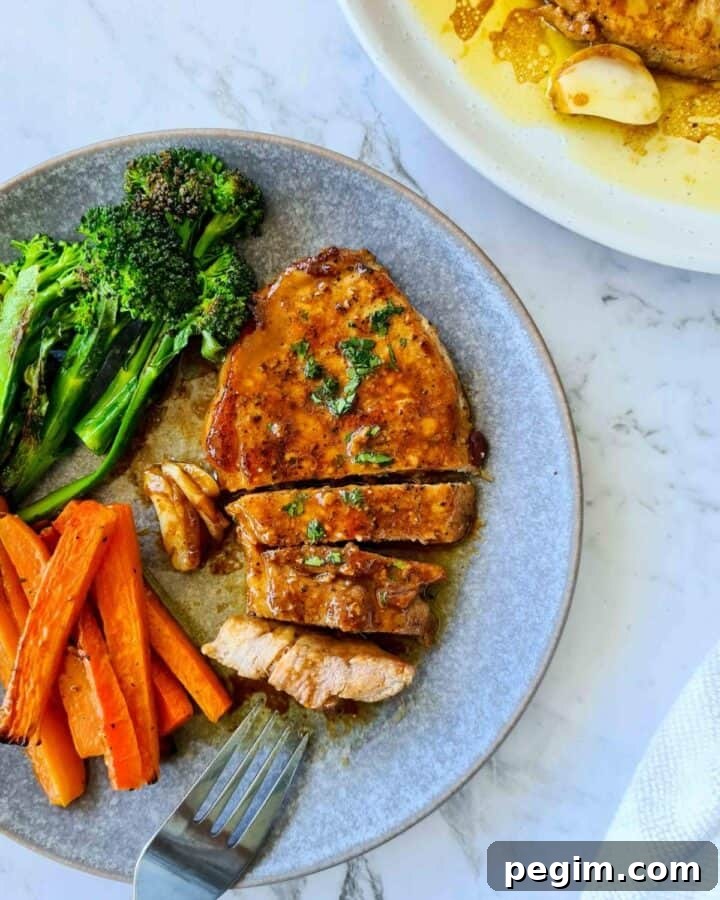 Pork chop on a serving dish, thickly cut to bite size with a side of grilled carrots sticks and broccolini
