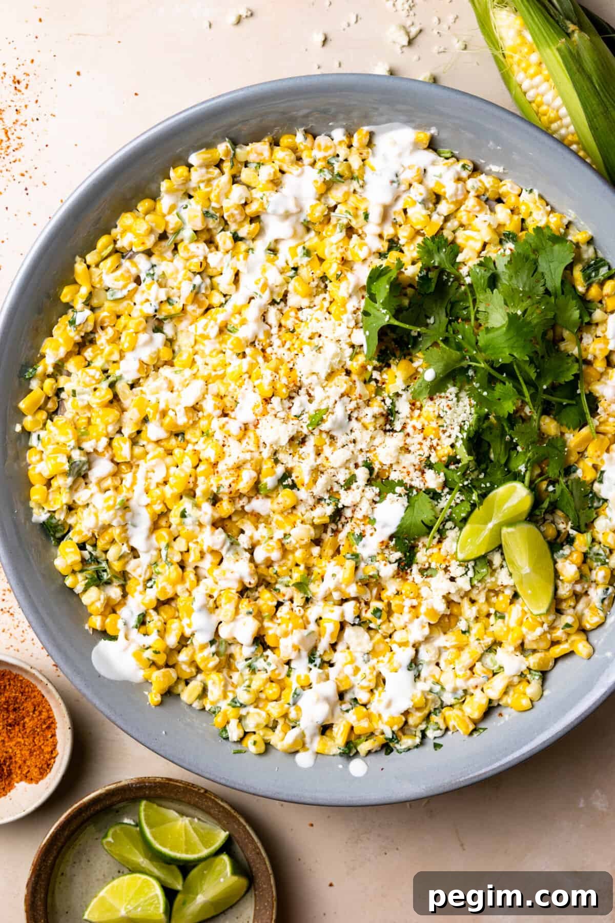 Mexican Street Corn Salad in a bowl topped with drizzled crema and crumbled cotija cheese.