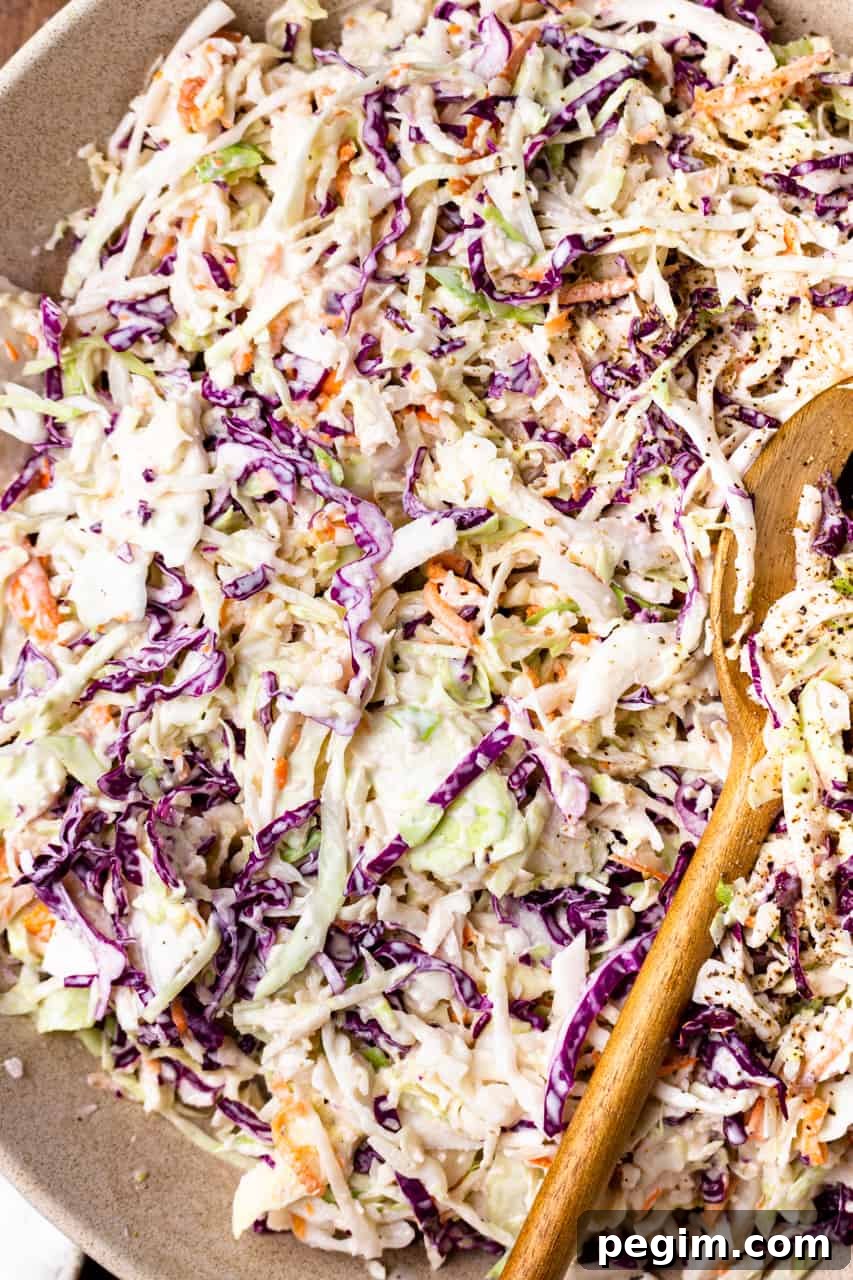 Up close view of mixed together coleslaw being served with wooden spoons.