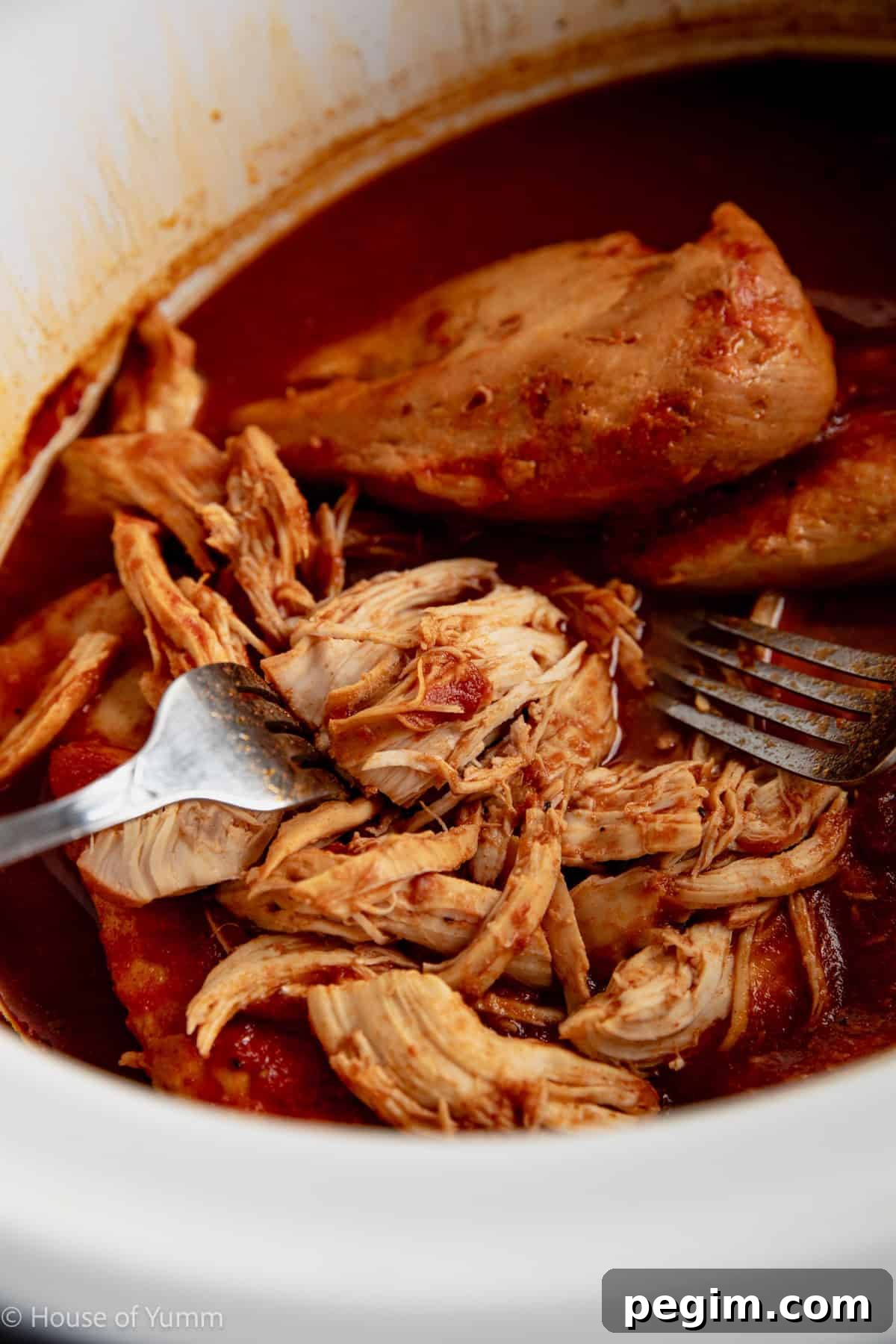 Shredding chicken in a slow cooker with two forks.