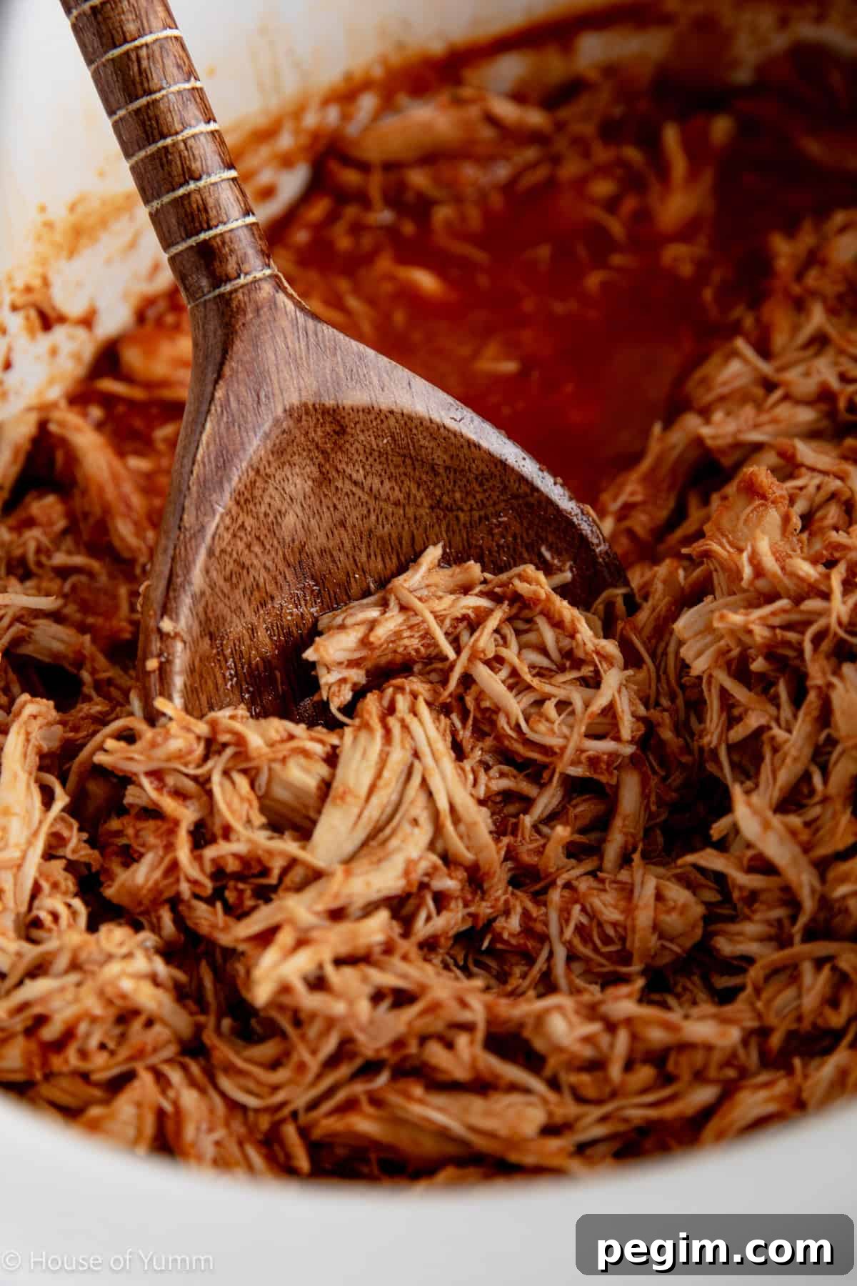 Spoon serving up bbq shredded chicken from slow cooker.