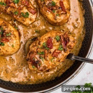 Creamy chicken in a large skillet with a spoon lifting a piece out of skillet.