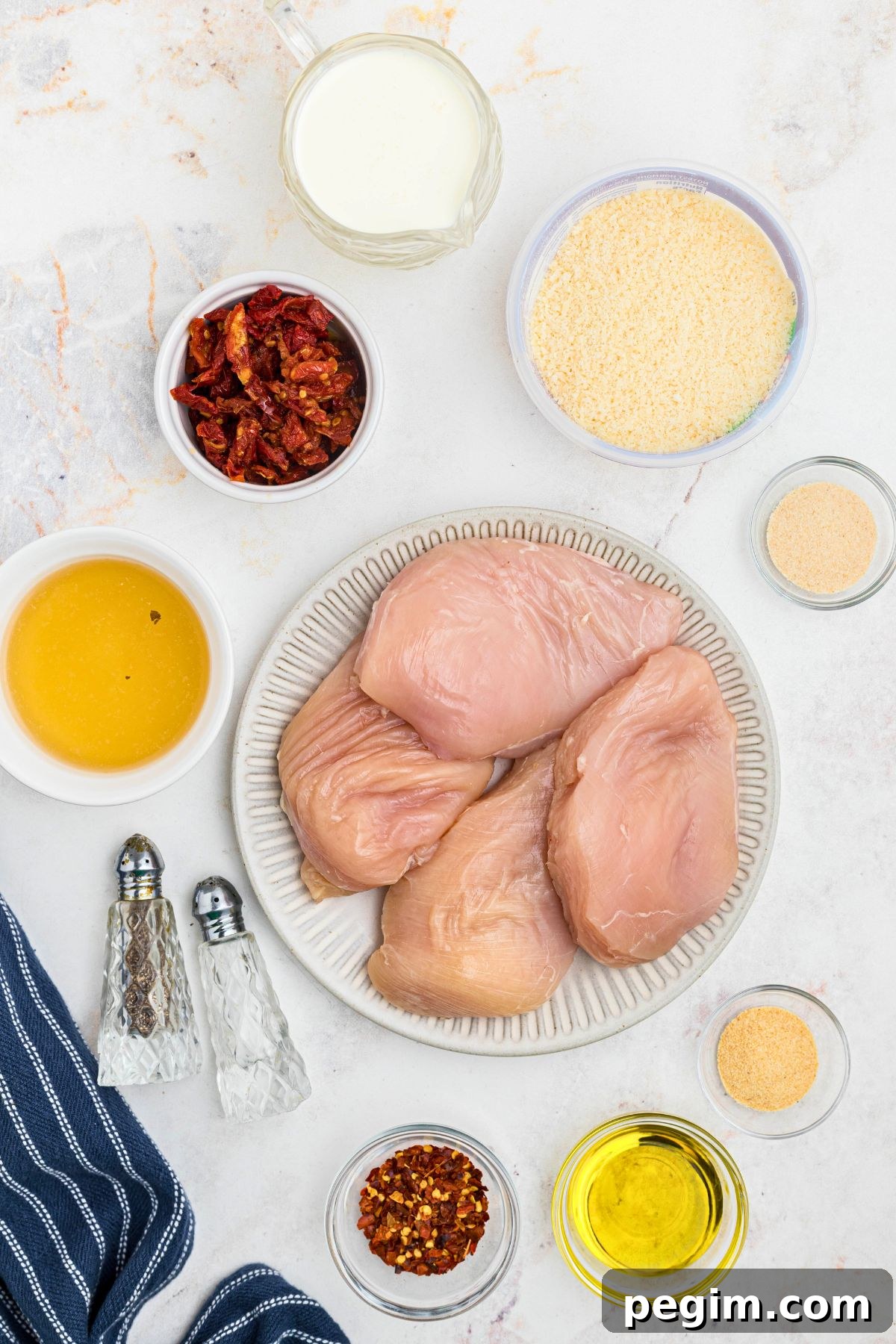 Ingredients needed to make Marry me Chicken measured into small bowls, on a marble table. 