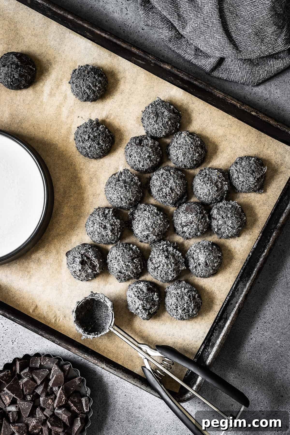 Scooped black sesame cookie dough on a parchment lined baking sheet.